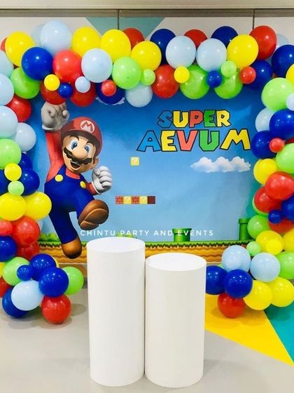 A vibrant Super Mario theme birthday party with a classic game-level backdrop. The scene is framed by a colorful balloon arch perfect for photos.