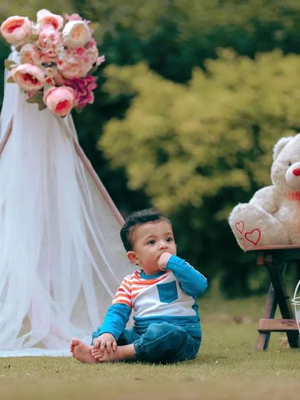 A relaxed outdoor portrait of a little boy enjoying a picnic-style setup. The natural background and soft lighting create a beautiful, timeless look.