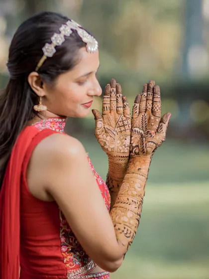 The bride brings her hands together, creating a beautiful frame to admire her Mehendi design.