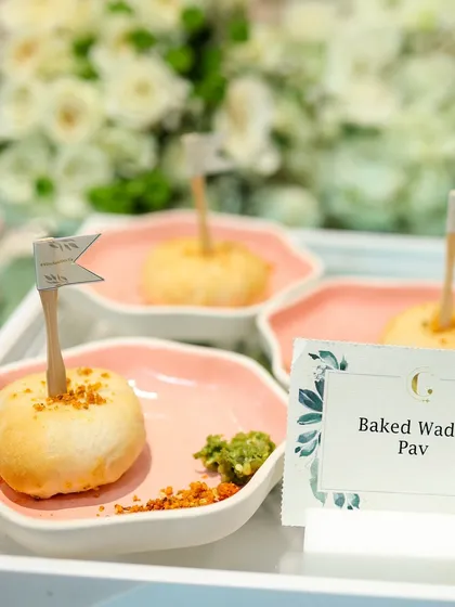 Our Baked Vada Pav, individually plated and garnished with a mini flag. This playful presentation elevates a beloved street food into a sophisticated appetizer for corporate events.