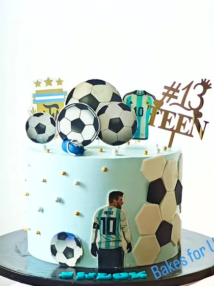 An Argentina and Messi-themed football cake for a 13th birthday. The light blue cake is decorated with soccer balls and edible images of the football star.
