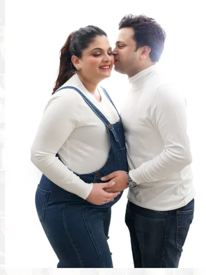 Sometimes the simplest moments are the most beautiful. This sweet, intimate portrait of an expecting couple was part of a casual studio session. Their coordinated white tops and denim create a timeless, relaxed look against a clean white background.