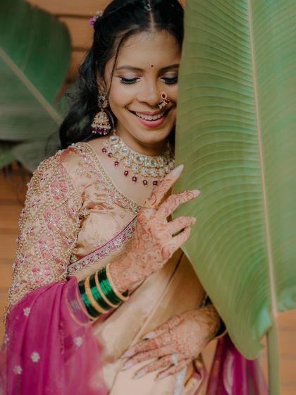 A playful and shy smile from the bride, Karishma. Her intricate henna, Maharashtrian nath, and the vibrant green bangles are the focus of this beautiful shot.