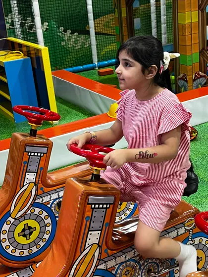 A girl takes a spin on one of the ride-on toys, perfect for imaginative journeys around the play area.