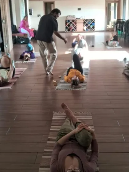 An instructor offers personalized correction on alignment during a group class. We prioritize safe and effective practice by ensuring each student understands the mechanics of the asana for their own body.