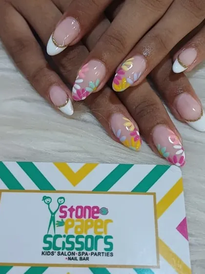 A modern twist on a classic. This is a white-tipped French manicure on almond nails, updated with delicate, hand-painted floral designs for a fresh, spring vibe.