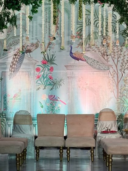 The main seating area of a Pichwai-themed mandap, with the beautiful painted backdrop creating a serene and artistic setting for the couple.