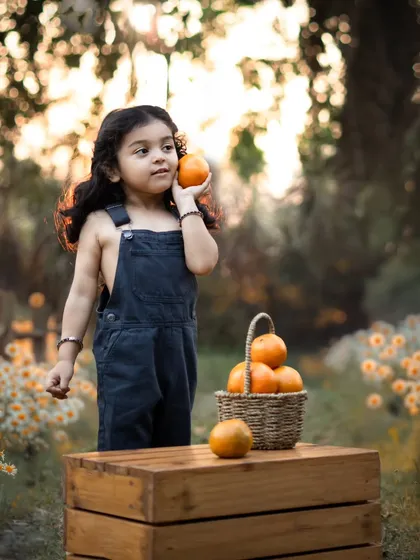 An orange-themed outdoor shoot. This little boy is pretending to take a call on an orange, a perfect example of the sweet, imaginative moments we can capture.