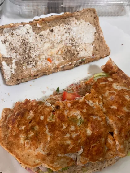 This is my idea of a perfect Sunday meal. A multigrain sandwich filled with a fluffy omelette, fresh lettuce, cucumber, tomato, and onion. It proves that a balanced breakfast is the first step to a balanced life.