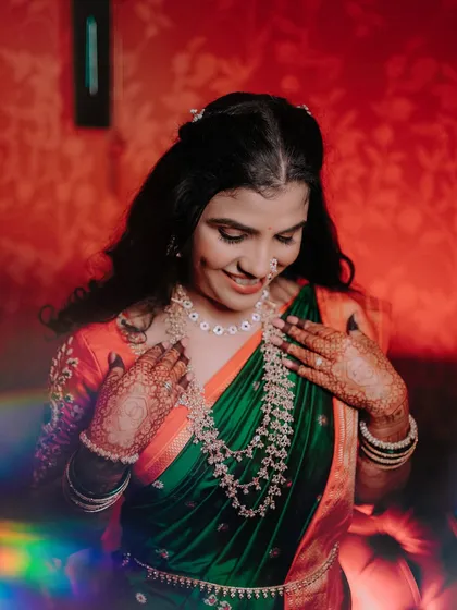 A lovely portrait of the bride in her green and orange saree. The soft, colorful light leak adds a dreamy and artistic touch to the photo, capturing her gentle smile.