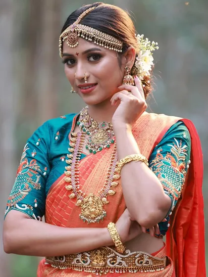 I love capturing the timeless grace of a traditional bridal look. This outdoor shoot focused on the intricate details of the temple jewellery and the rich texture of the orange and teal silk saree against a natural, wooded backdrop.