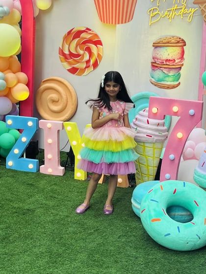 A full view of our Candyland-themed party dress. The colorful decor perfectly complements the rainbow tulle skirt and sweet details of Ziya's 7th birthday outfit.