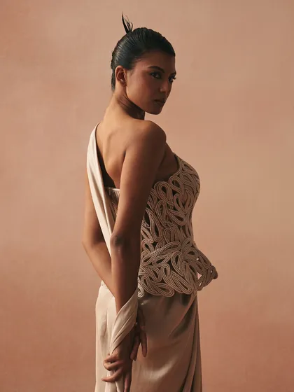 The Karov gown, where paisley rendered in zari cords on a cotton corset becomes the anchor. The satin drape skirt lets movement soften the garment’s sculpted intent.