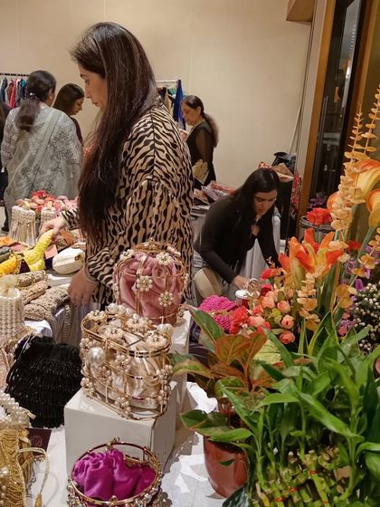 A beautifully decorated stall featuring ornate handbags and accessories, attracting a discerning shopper.