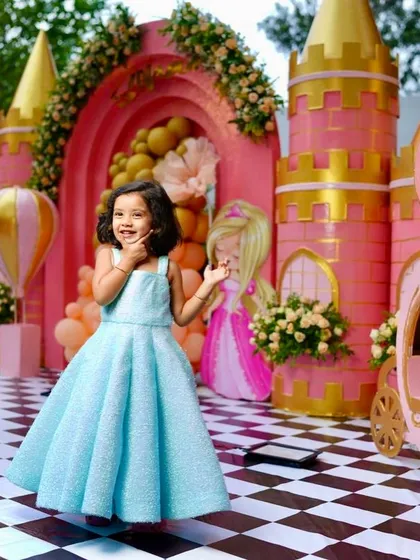 The birthday girl, Soha, looking like a real princess in her blue dress, twirling in front of her magnificent pink and gold castle.