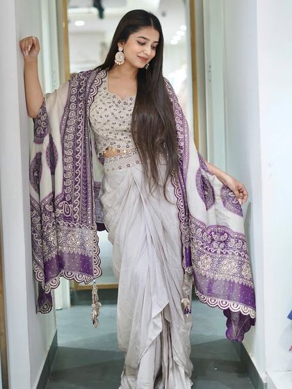 A dhoti, blouse, and cape set perfect for wedding functions. The intricate purple embroidery on the cape adds a touch of royalty.