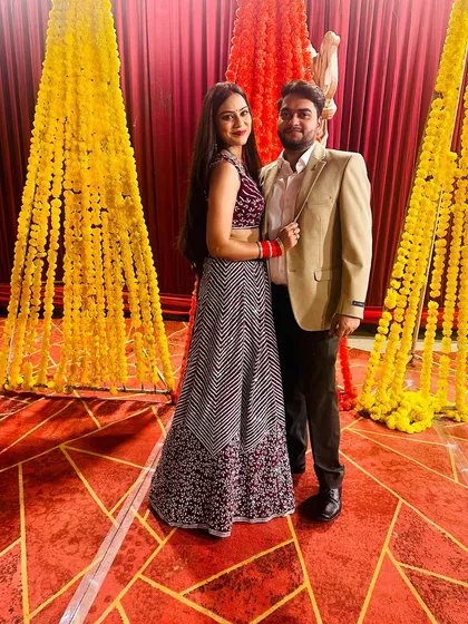 A full-length shot of the couple against a festive backdrop of marigold flowers.