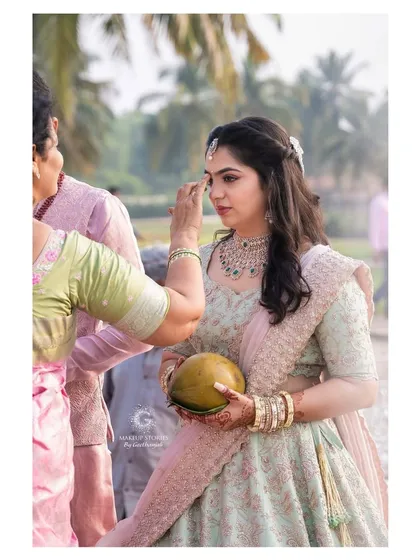 A candid moment from Reshma's engagement puja. Her makeup is subtle and flawless, ensuring she looks beautiful and feels comfortable throughout the traditional rituals.