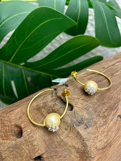 A modern take on classic hoops. These earrings feature a single pearl accented with a cluster of small stones, a perfect blend of simplicity and sparkle.