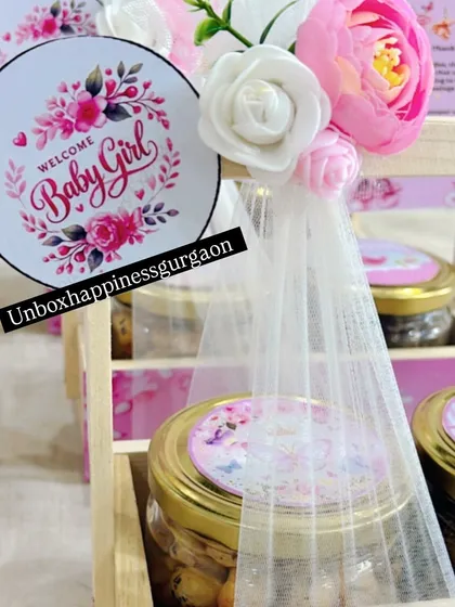 A close-up on the "Welcome Baby Girl" tag and floral decoration, highlighting the handmade touches that make each favor special.