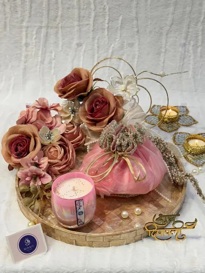 A romantic and elegant Diwali hamper in shades of pink. This beautiful arrangement includes a scented candle, a floral 'potli', and decorative 'diya' holders on a mother-of-pearl inlay tray.