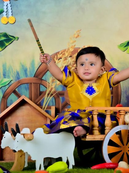 A baby in a traditional farmer's outfit, looking joyful and energetic.