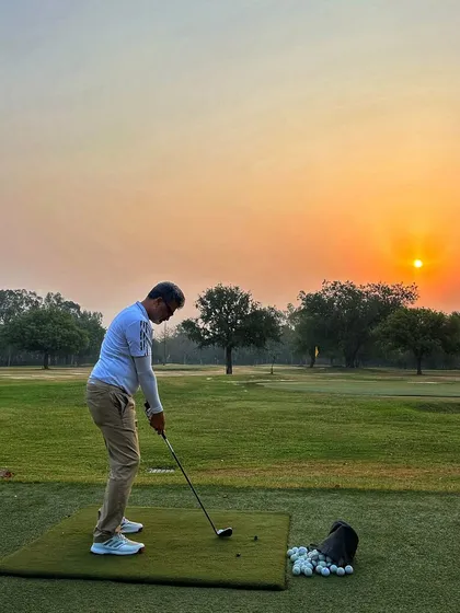 A lone golfer practices against the setting sun, a peaceful and beautiful end to the day.