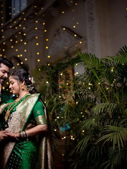 A romantic, softly lit portrait of a couple surrounded by fairy lights and greenery.