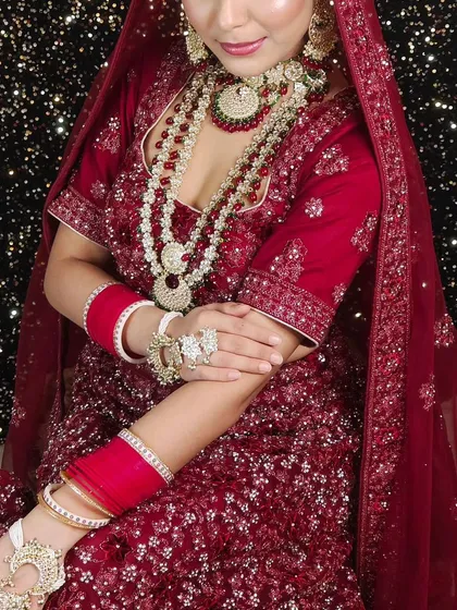 A beautiful maroon lehenga with all-over sequin work, paired with a layered ruby and pearl necklace set. This is a great option for a glamorous wedding reception.