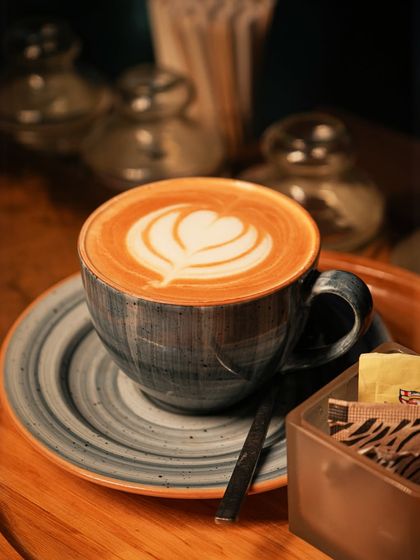 A perfect cup of cappuccino with beautiful heart-shaped latte art, served on a wooden tray.