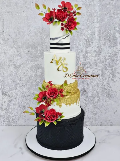 A full studio shot of the modern black, white, and gold wedding cake. This view highlights the clean lines, the contrast of colors and textures, and the carefully placed floral arrangements.
