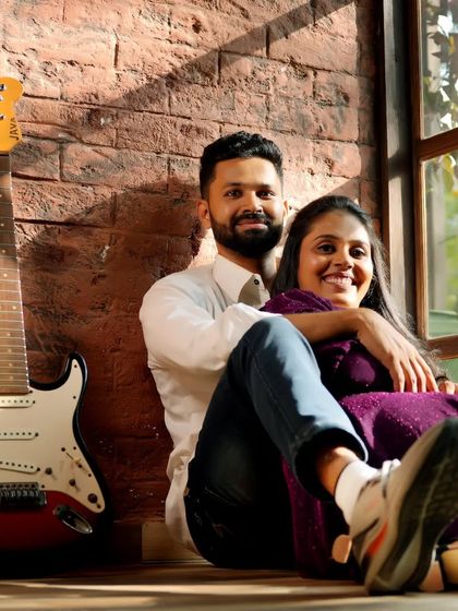 A cool and casual indoor portrait. The brick wall and guitar prop give this shot a relaxed, rustic, and musical vibe.