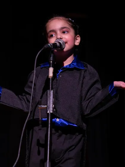 Another confident young speaker at the microphone, using expressive gestures to engage the audience.