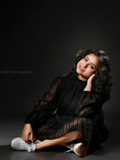 This full-body studio portrait offers a more relaxed and casual feel. It's a great way to showcase personal style, from the dress to the sneakers, creating a relatable image for the brand's audience while maintaining a professional studio quality.