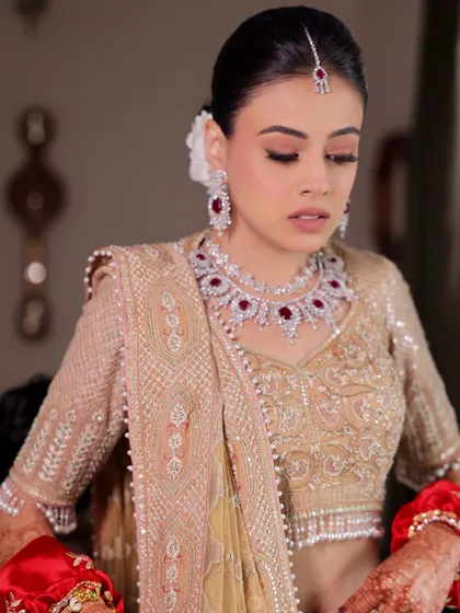A candid moment of the bride getting ready. The soft, elegant updo with a fresh white flower is the perfect complement to her ruby and diamond jewelry.