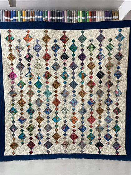 A beautiful Chandelier quilt with colorful diamond shapes cascading down a cream background.