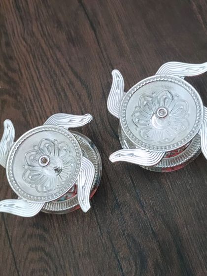 A pair of German silver swastik-shaped kumkum holders. The swastika is a symbol of good fortune and well-being.