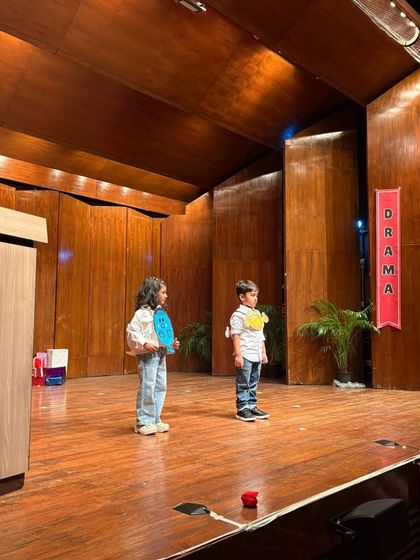 Two students stand on opposite sides of the stage, setting up a scene about connection and distance.