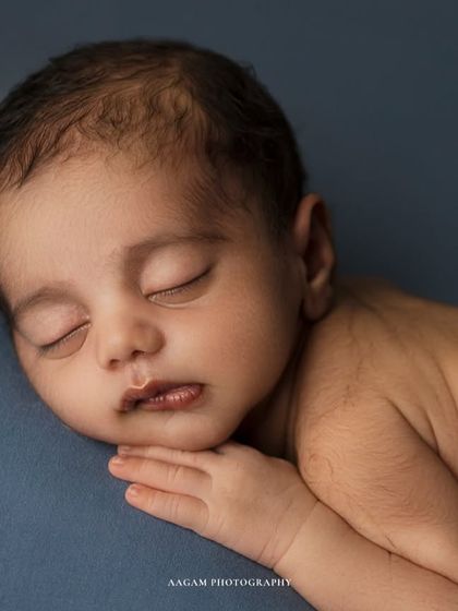 A close-up of a sleeping newborn, showing the delicate features and peaceful expression. The simple blue background provides a soft, calming feel.