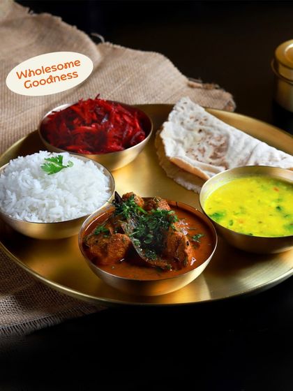 Another angle of our delicious non-veg thali, highlighting the rich texture of the chicken curry and the vibrant colors of the accompanying dishes. Wholesome goodness guaranteed.