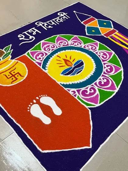 A classic Diwali rangoli design for a home entrance. It includes all the traditional elements: a 'kalash' for prosperity, Goddess Lakshmi's footprints to welcome her, a 'kandil' lantern, and a central diya, all set against a rich, dark background.