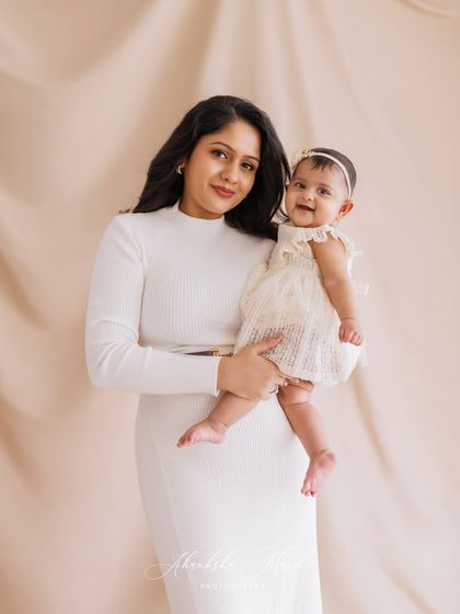 A beautiful portrait of this mother and her smiling baby. Their coordinated white outfits and the mother's loving hold create a classic and heartwarming image.