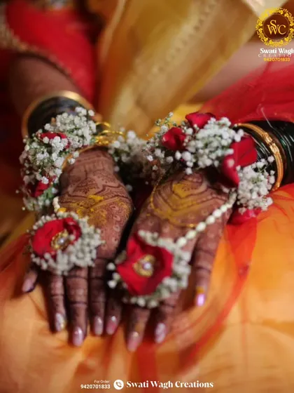 The beauty is in the details. This close-up shows the intricate work that goes into each hathphool, combining delicate baby's breath with bold red flowers to create a stunning contrast against the bride's henna.
