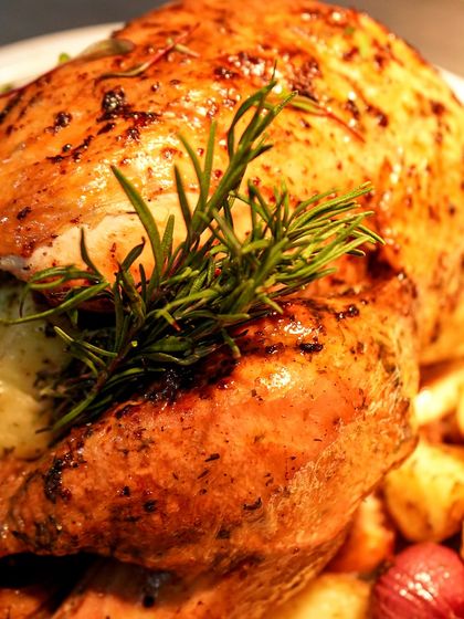A perfectly roasted turkey, garnished with fresh rosemary. This is the star of our Thanksgiving menu, available for both dine-in and home delivery.