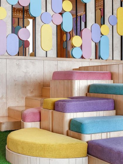 A close-up of the multi-level seating at Nivriti playschool. The steps are fitted with colorful, custom-sized cushions, creating a fun and comfortable amphitheater-style space for children. All corners are rounded for safety.