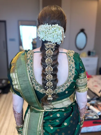 A full back view of the bride in her green Kanjeevaram saree, with the ornate temple jewellery braid as the centerpiece of her look.