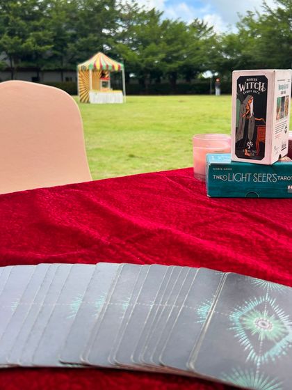 My reading table at the Hitachi event, set against the backdrop of a sprawling lawn. I always bring a selection of decks, like The Light Seer's Tarot and the Modern Witch Tarot, to match the energy of the event.