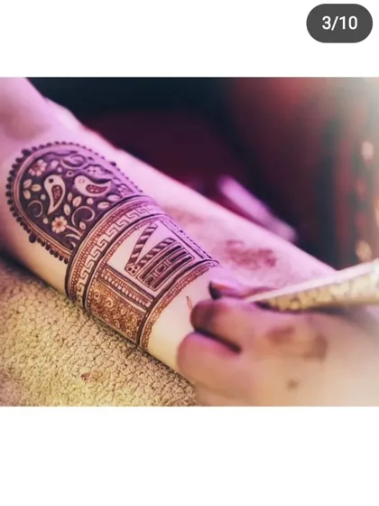 A close-up of a student applying a custom design on an arm. This piece features a movie clapperboard, showing how we can incorporate personal themes into mehendi.