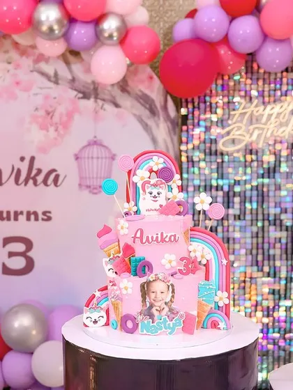A close-up of a fun and colorful three-tiered cake for a third birthday, showcasing the playful decorations.