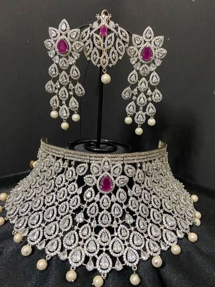 This grand choker set with a matching headpiece (passa) is designed for a glamorous look. The combination of white and red stones with pearl drops is perfect for a modern bride.